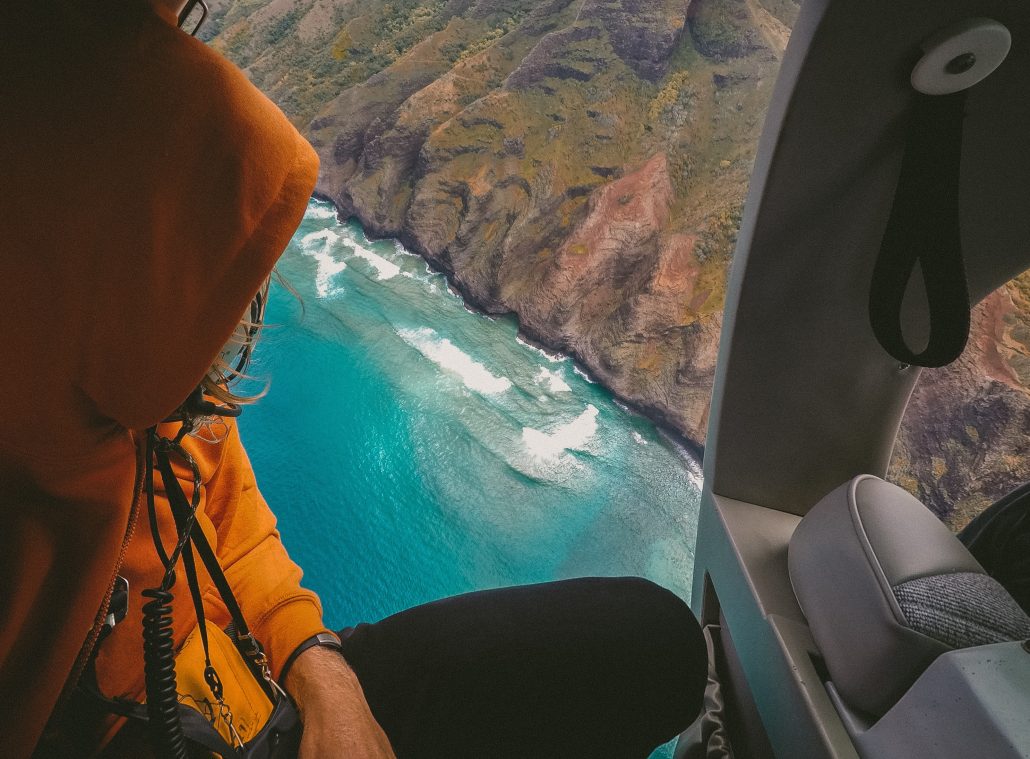 guy in helicopter over ocean and mountains unique experiences