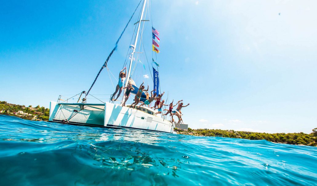 friends jumping off boat at the yacht week greece